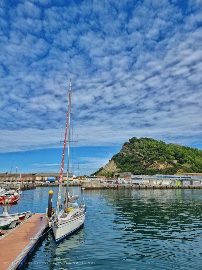 small boats in a marina, green hill behind