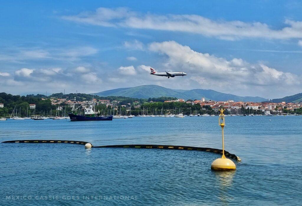 plane coming into land over calm sea, land in background