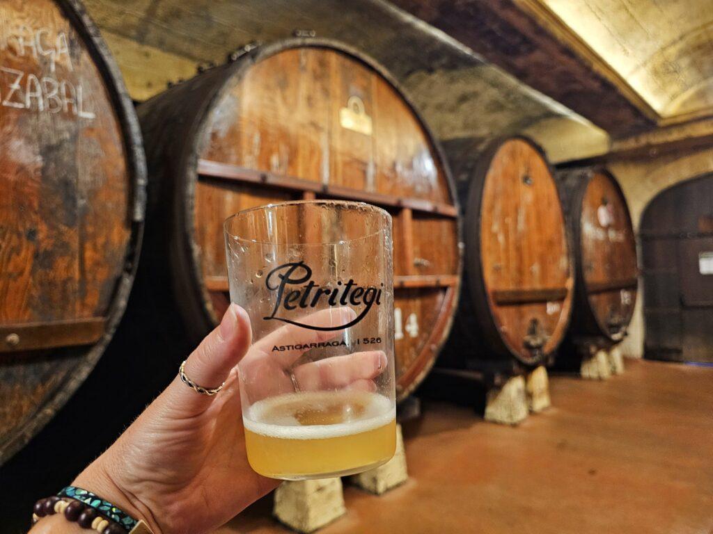 enormous wooden barrels and a hand holding a glass of cider