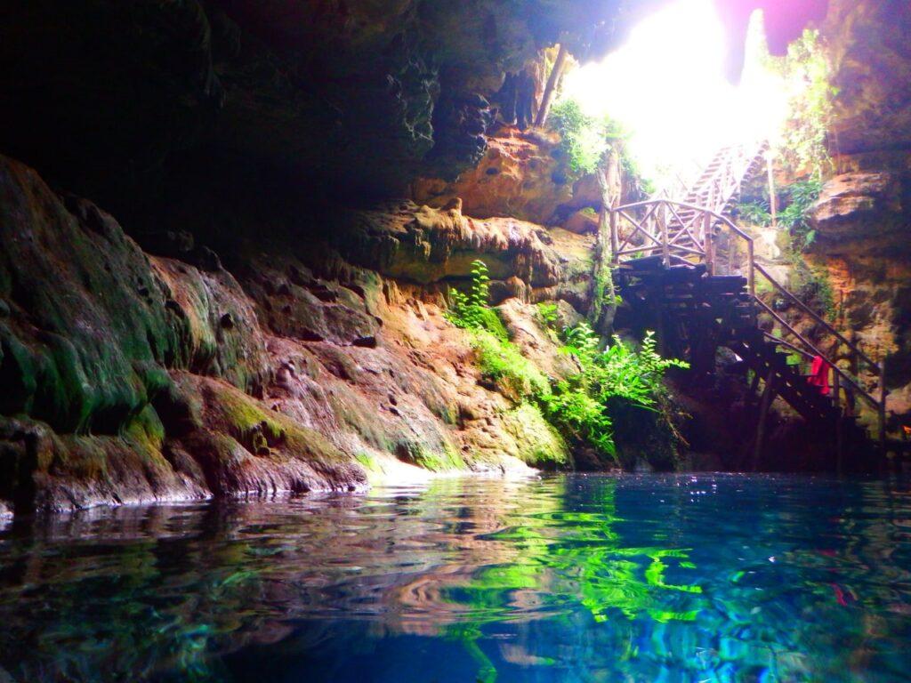 gorgeous blue water inside a cave, steps on far side of picture with opening to sky