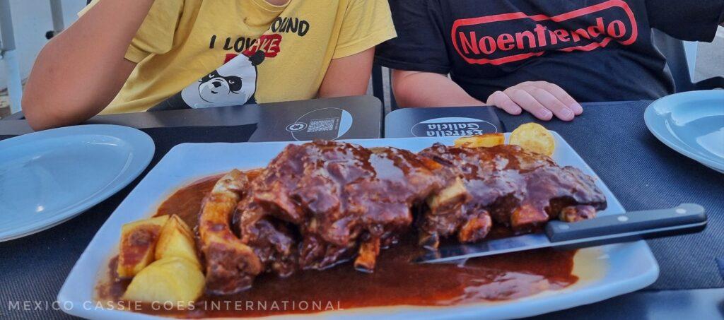 plate of ribs in sauce with kids behind them (faces not visible)