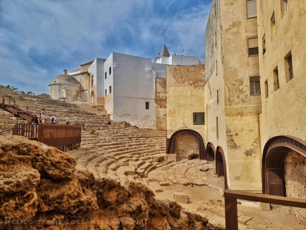 view over a ruined roman theatre - yellow brick buildings on right