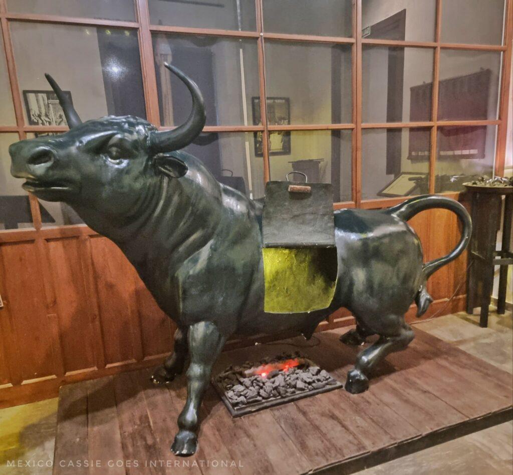 metal bull with an open section in its stomach area where people were placed. fake fire under this area.