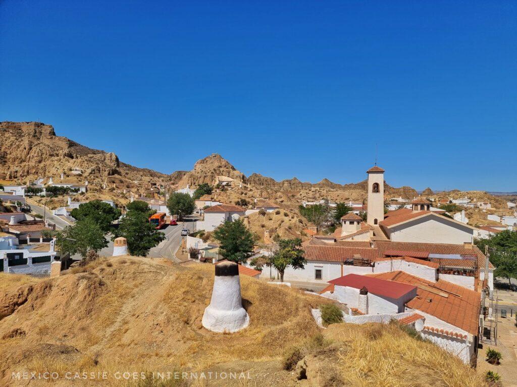 view over Guadix cave district - blue sky, white chimneys, bell tower