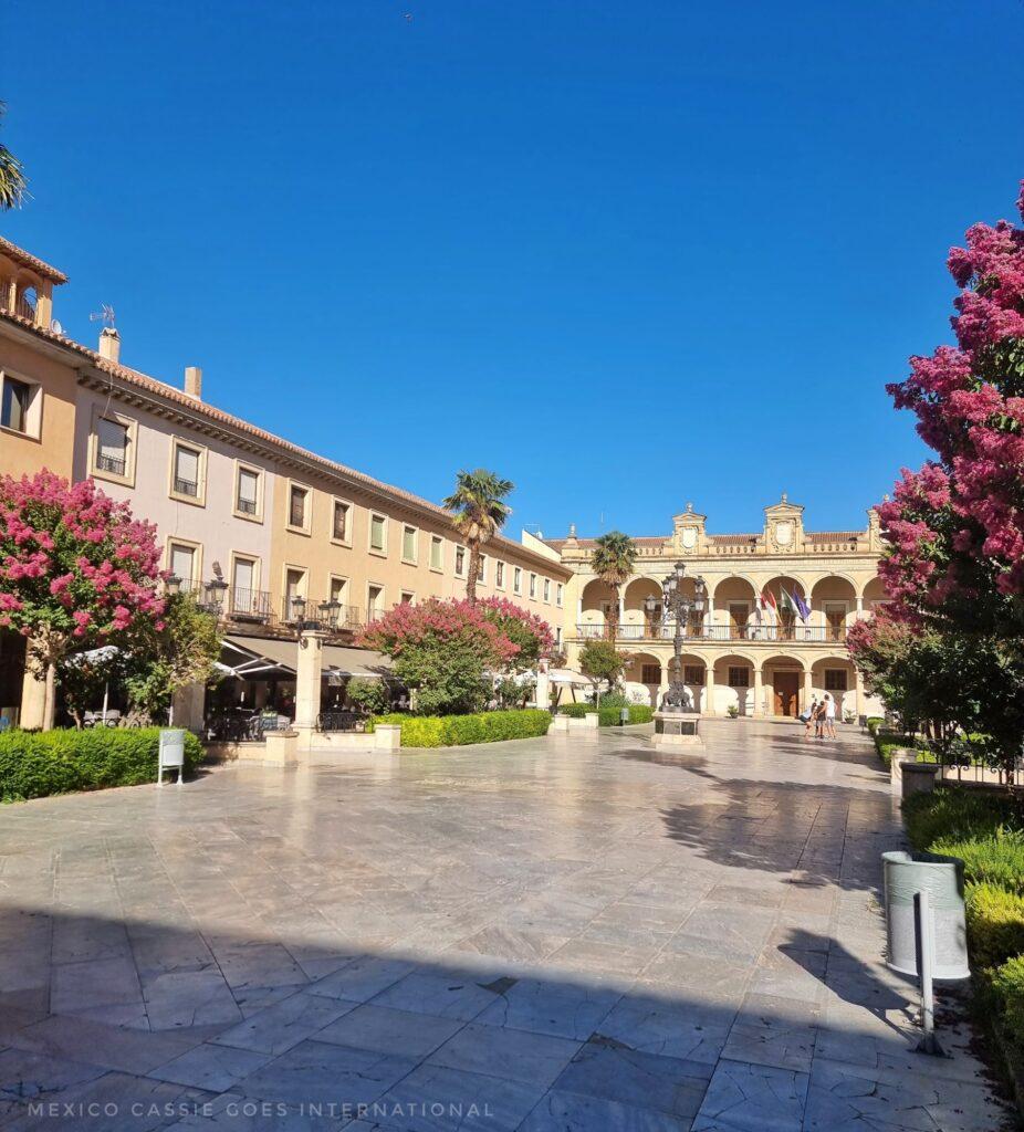 empty plaza on a bright summer's day - buildings around the edges, arches at far end