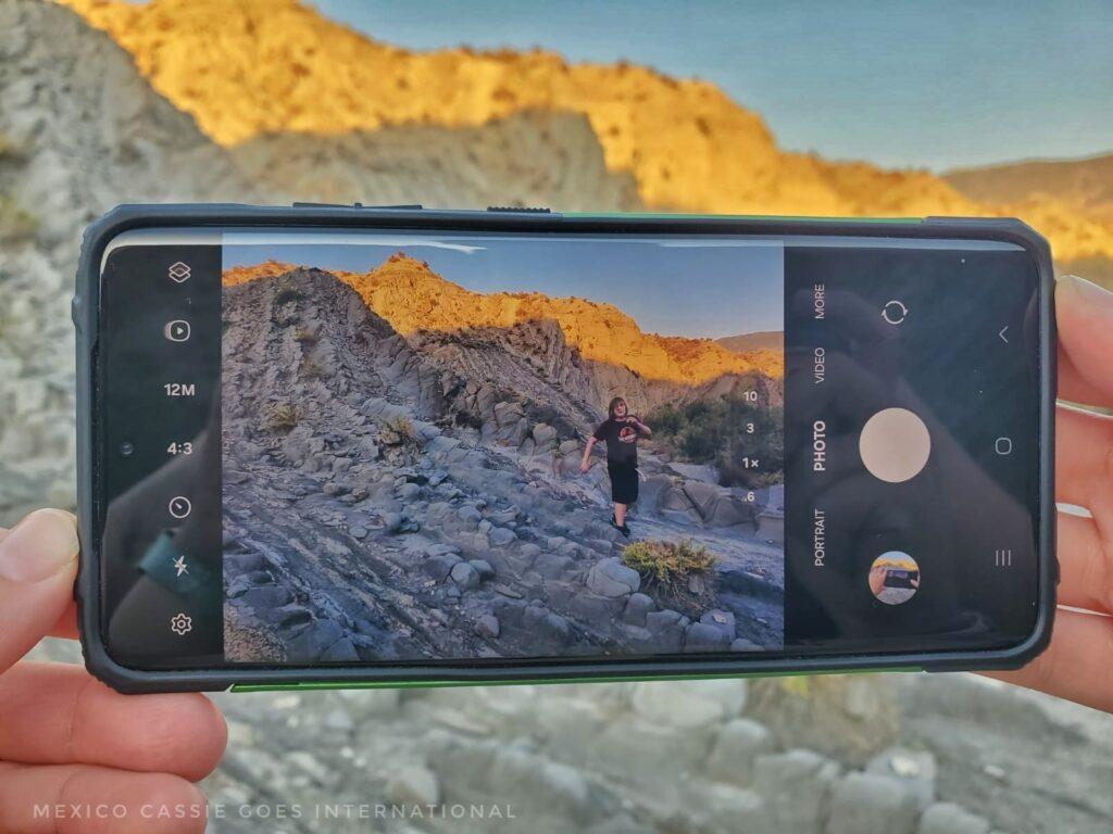 photo of a phone with a photo of a kid walking on rocks