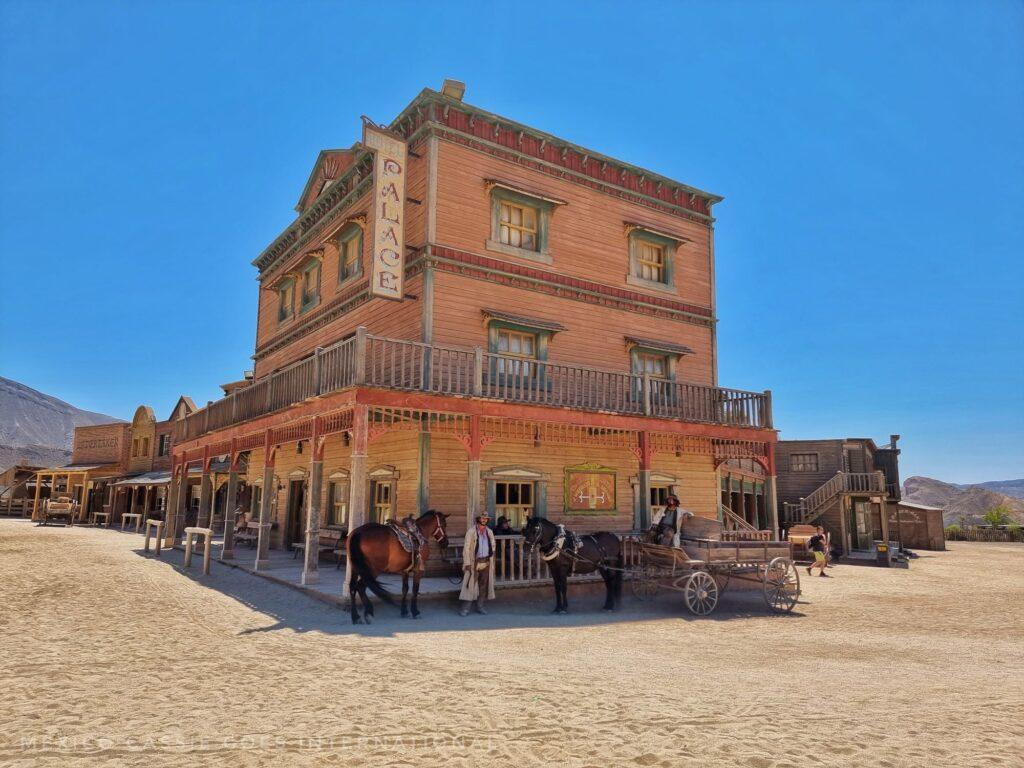 wild west style building with horses outside it. bright blue sky