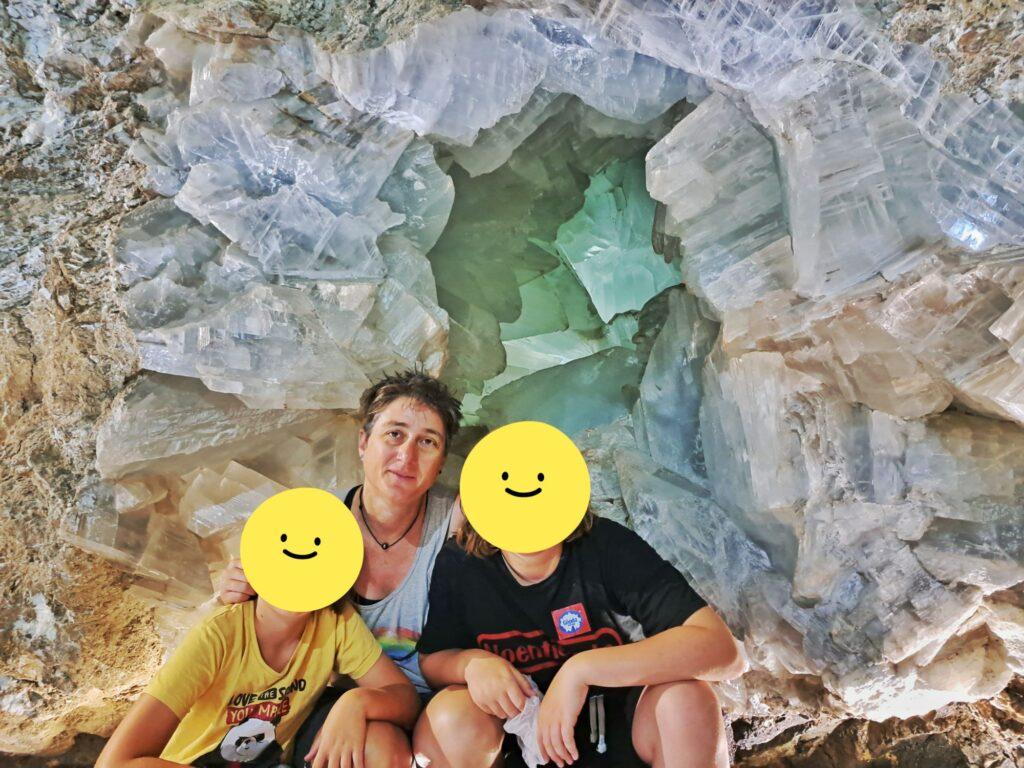 Cassie and 2 kids (yellow smily faces over their faces) sitting in front of the world's biggest geode