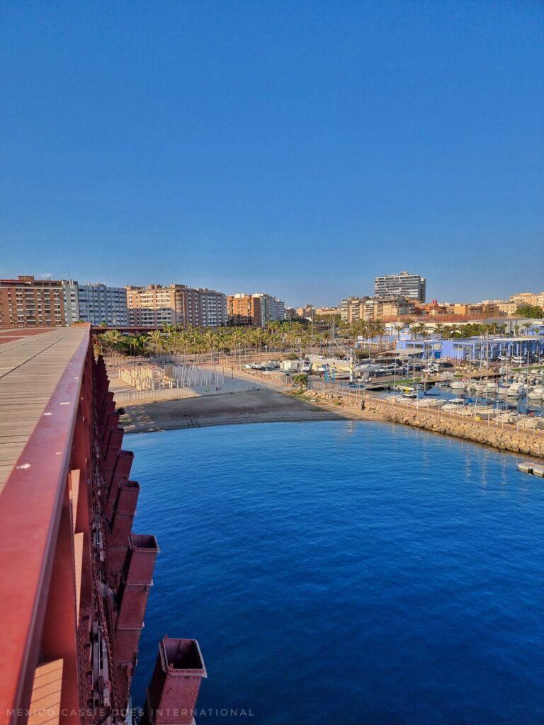 view of the cable inglés (red iron bridge), sea below it and some of the town