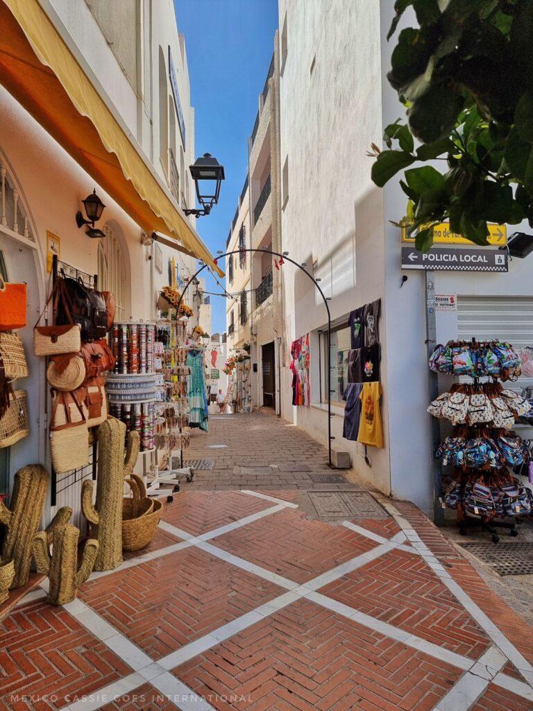 village street, path is red tiles with white crossing through, souvenirs hanging from shops