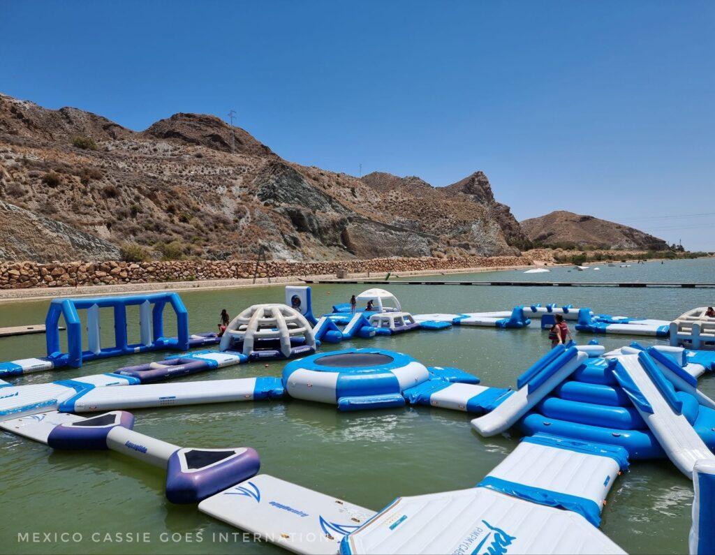 inflatable obstacle course (blue and white) on water with mountains behind