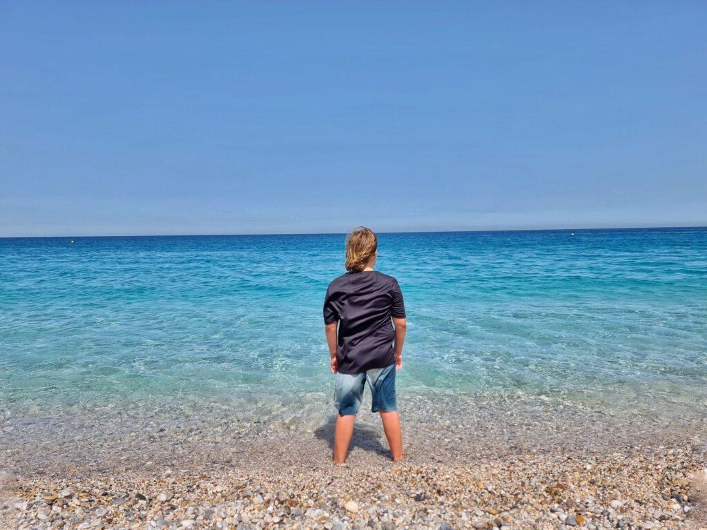 person in black tshirt standing in perfect, calm blue sea water