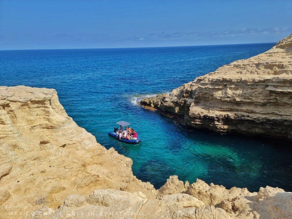 very blue water, people on a kayak. cliffs on either side