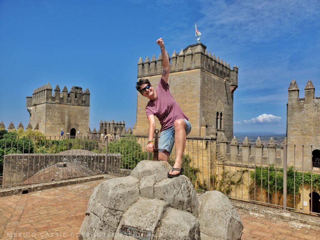 adult pretending to pull a sword out of a stone, castle towers behind