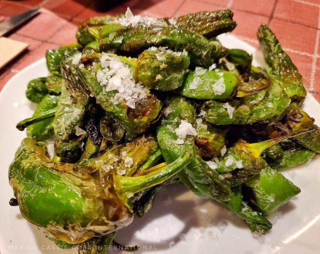 plate of cooked green peppers on a plate. Salt clearly visible