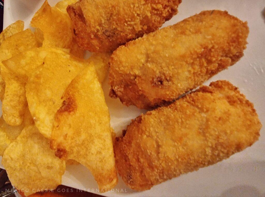 close up of 3 croquetas and some crisps on a plate