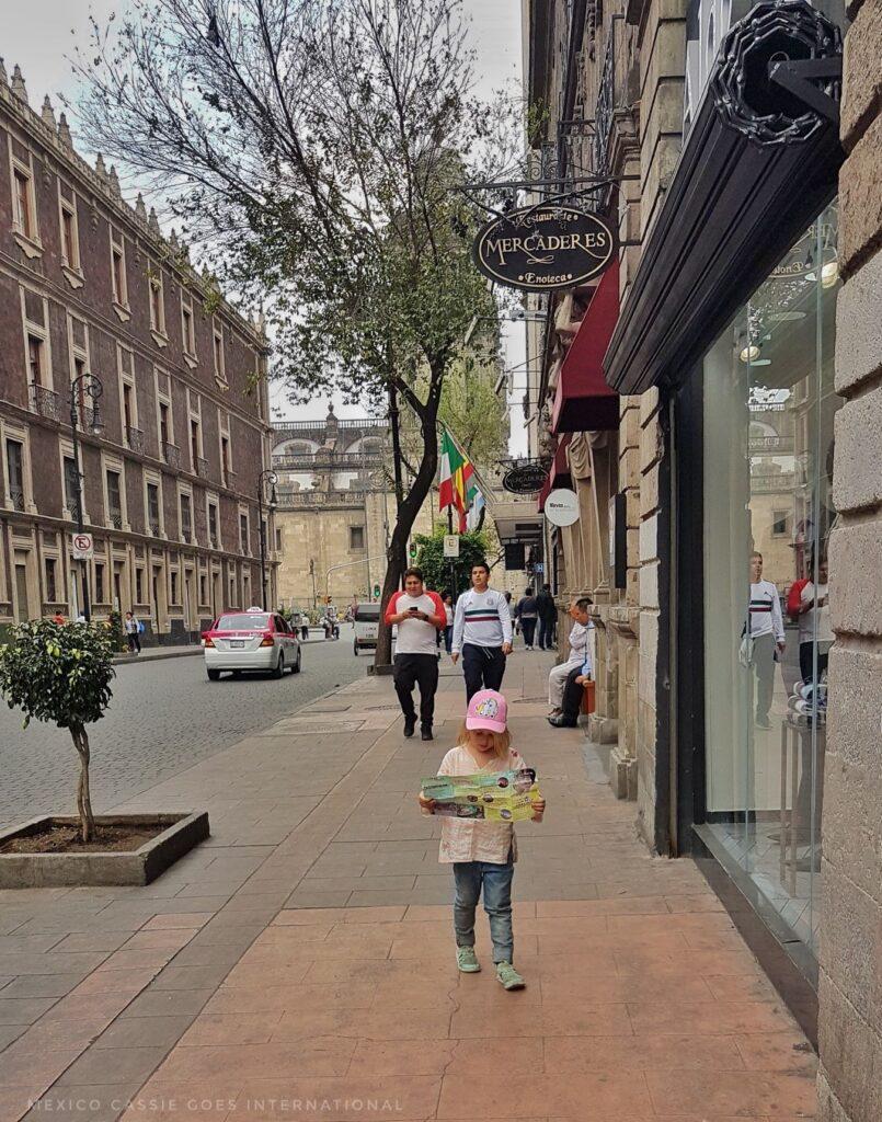 small child holding map alone on a city street