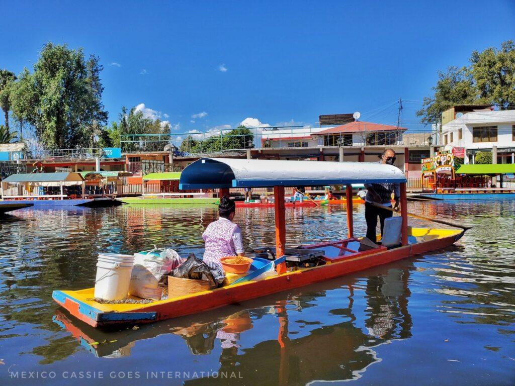 small red and yellow boat with person selling food on it