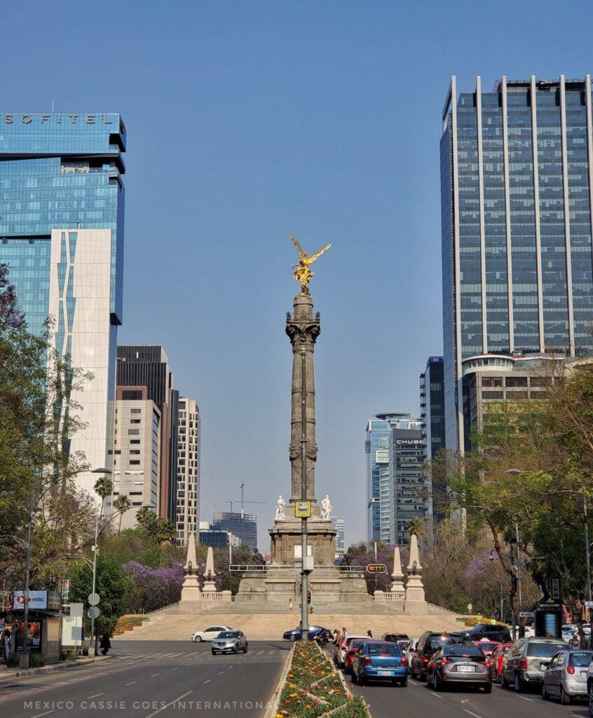 looking along Reforma in CDMX - Angel de la Independencia in front (column with golden angel on top), tall modern buildings all around