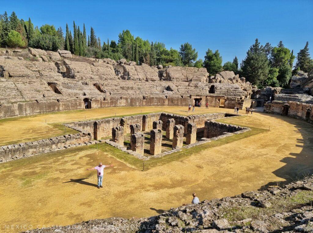 view down over a roman amphitheatre, columns in middle in a sunken area, 