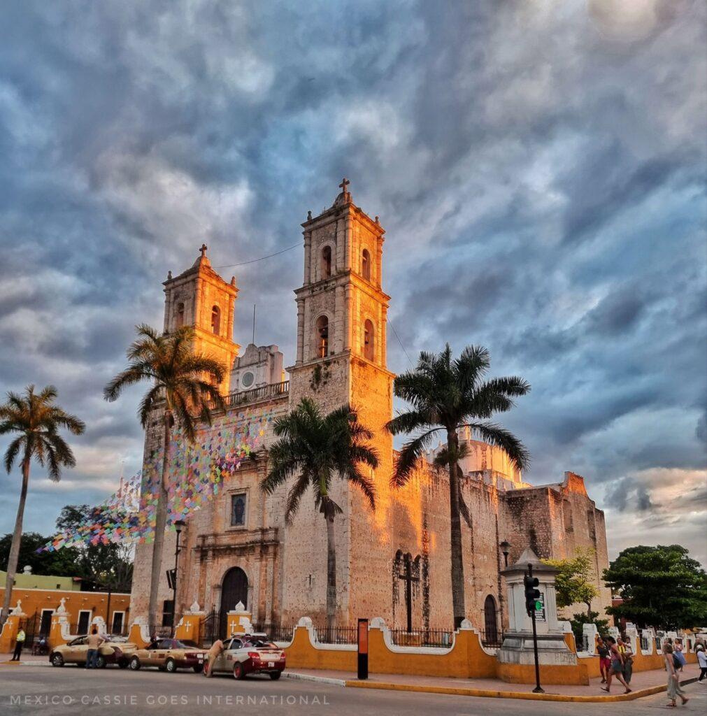 church with 2 towers as dusk approaches. 4 palm trees in front