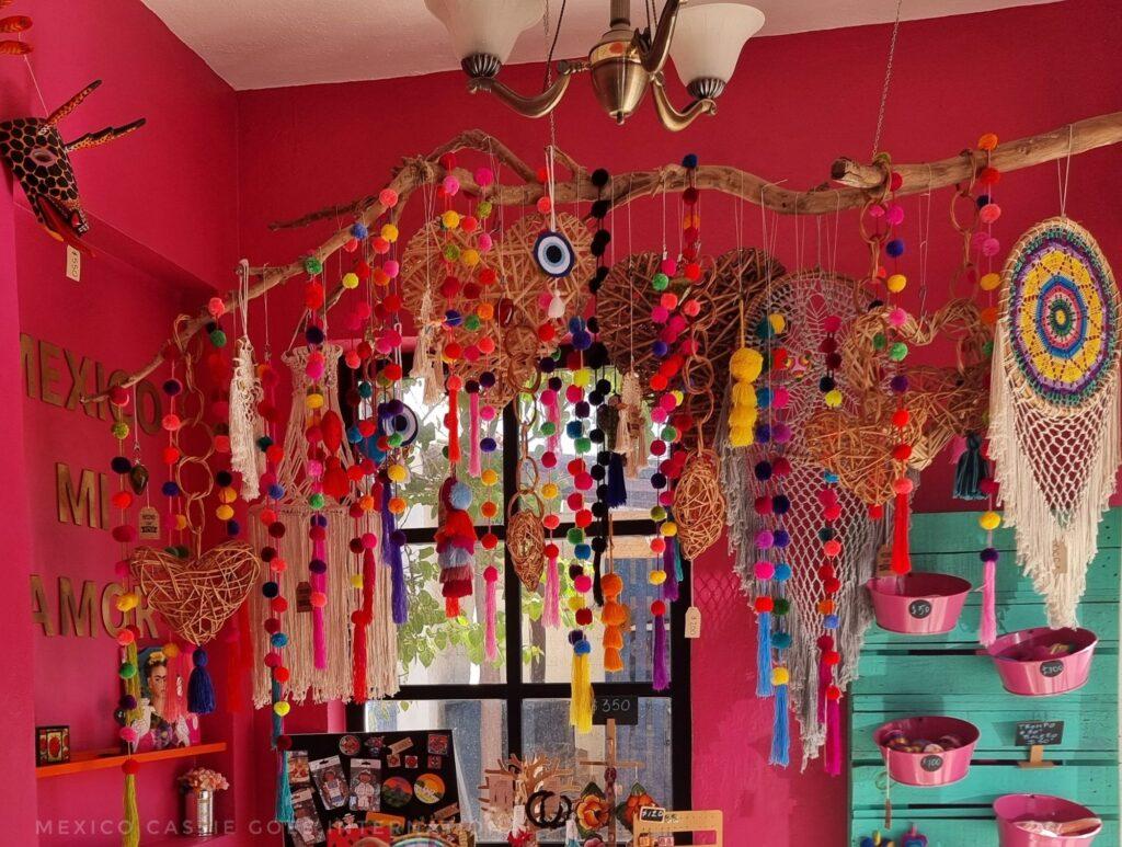 red walls in souvenir shop - wooden branch with pompoms etc hanging off it