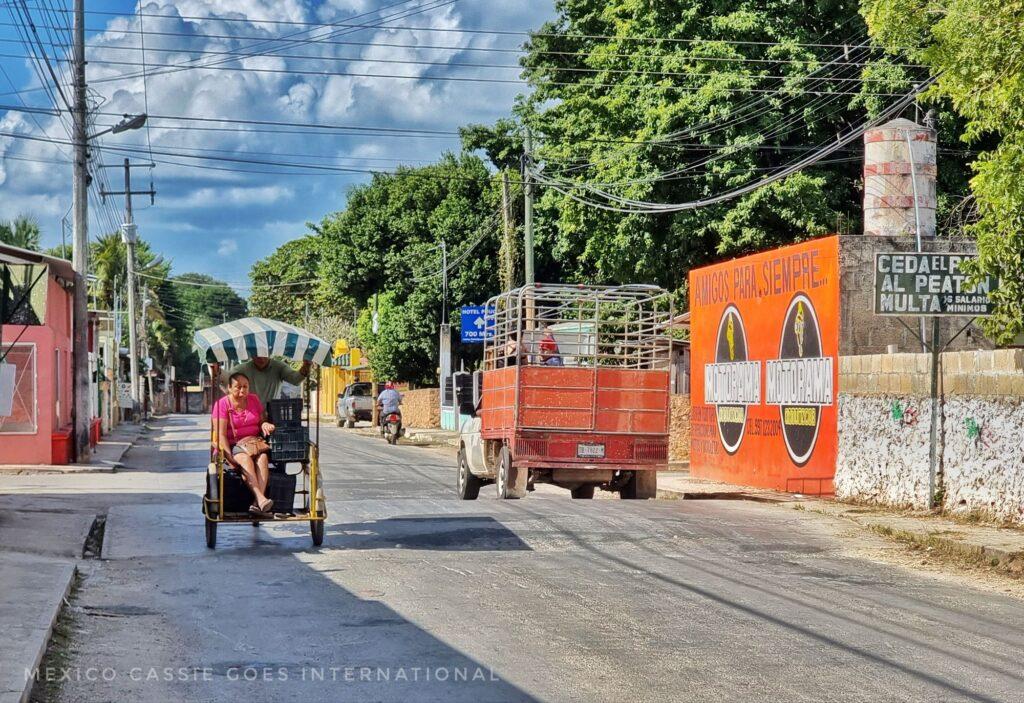 quiet road with parked truck, and 1 moto taxi driving