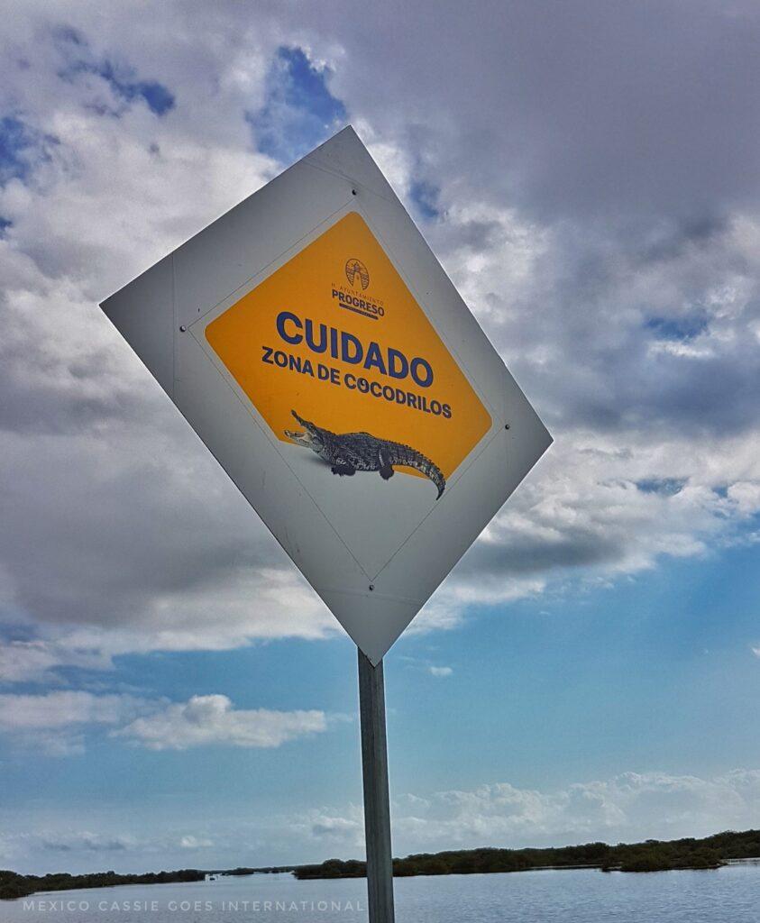 yellow sign readinig "cuidado, zona de cocodrilos" - "be careful, crocodile zone"