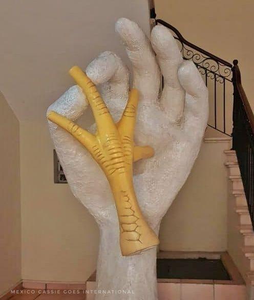 sculpture of a white hand holding a chicken leg