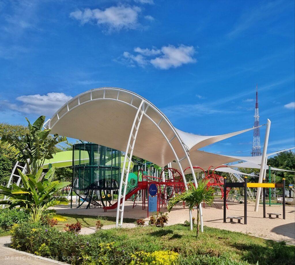 brightly coloured playground under a white sun protector on a blue and sunny day