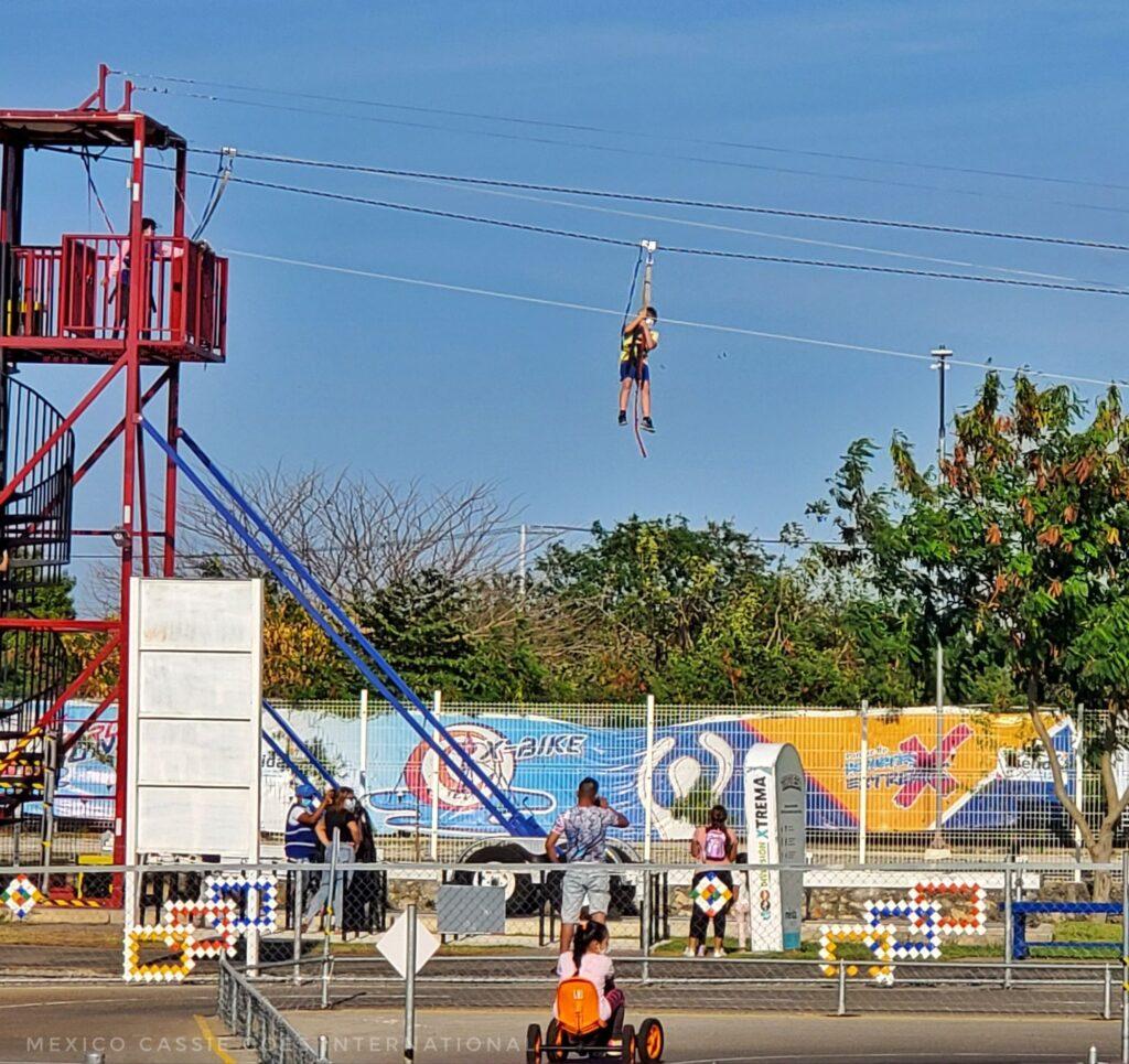 kid on a zipline flying over a kid on a go-cart