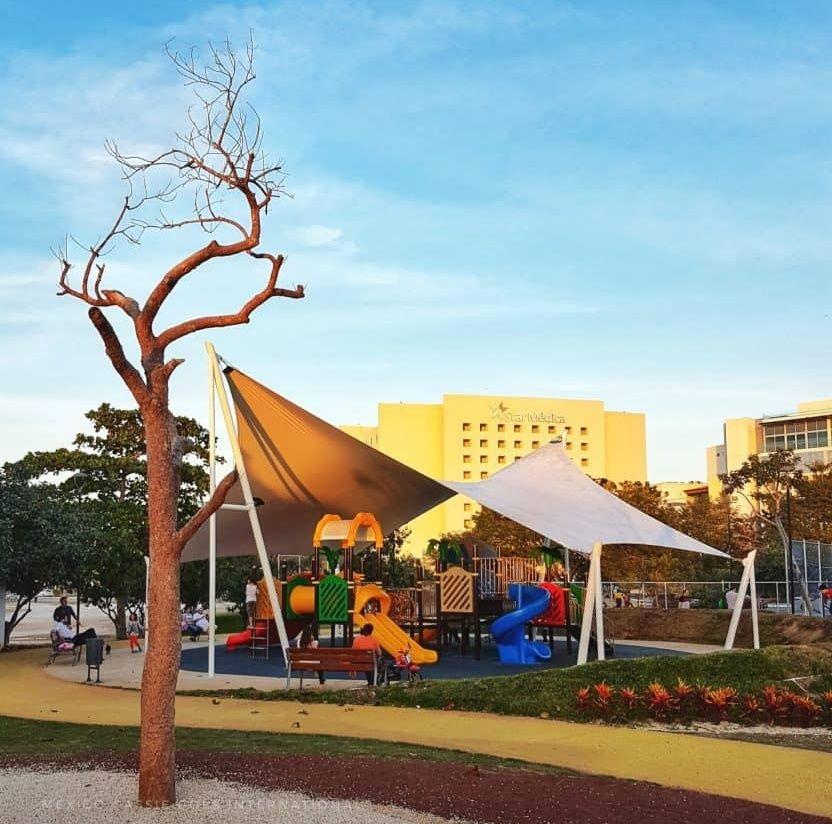 playground under a white sun shade, tree to left of screen