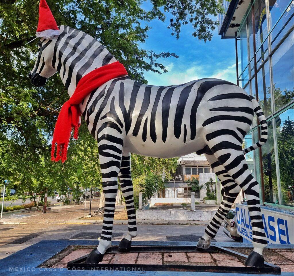 large zebra sculpture wearing red hat and scarf