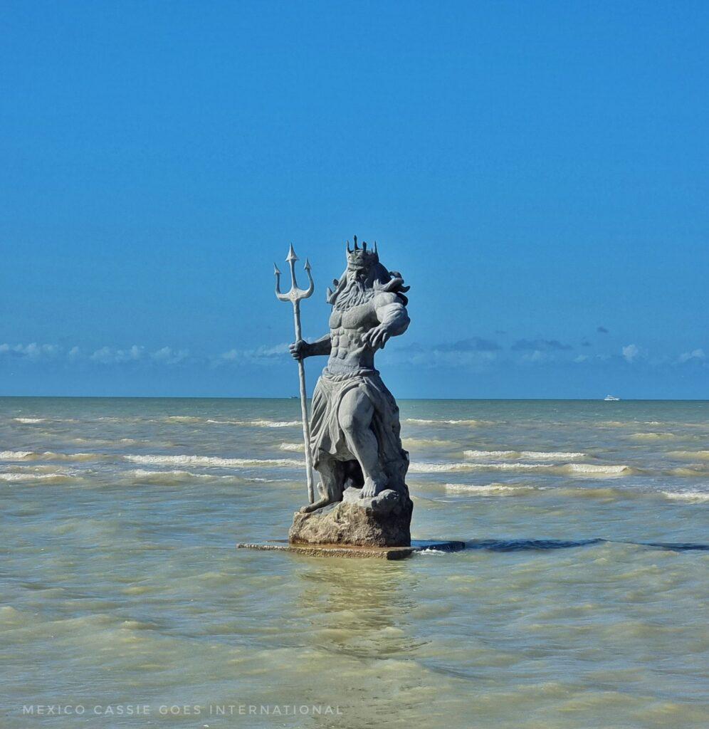 statue of posiden in shallow water with blue sky behind