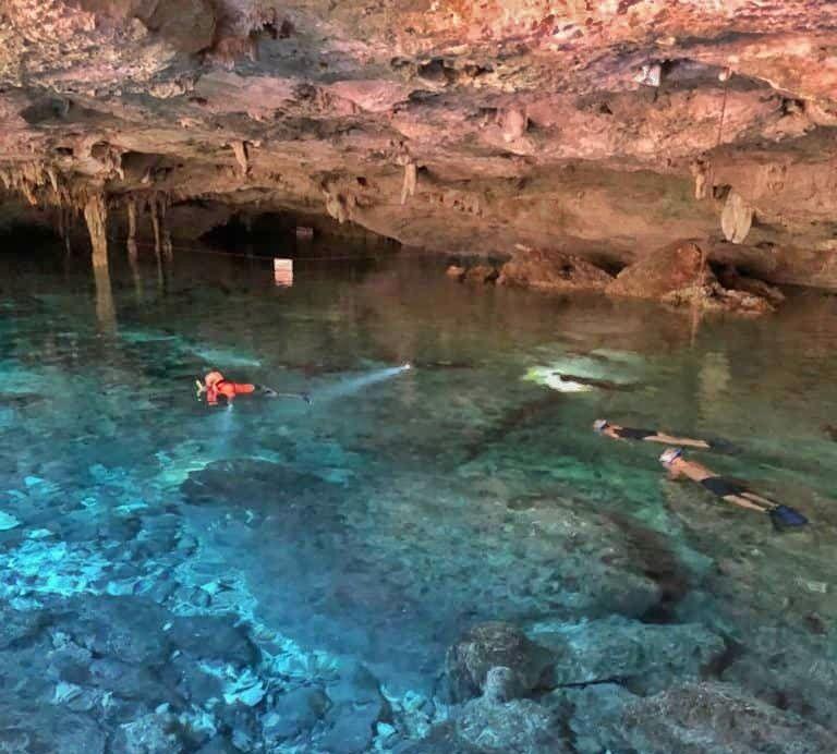 3 people snorkelling in a cave cenote