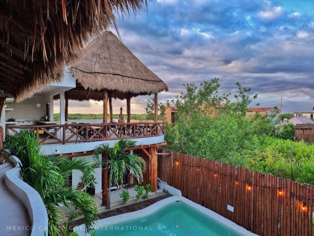 view over hotel pool at dawn - palapa roof on open air dining area