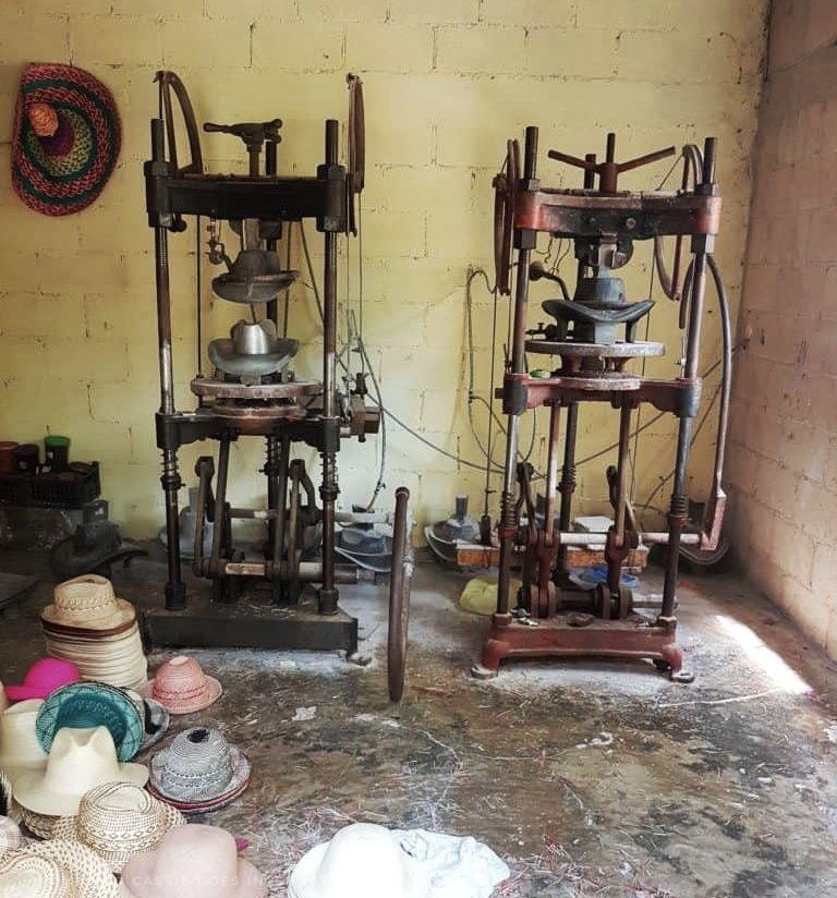 2 hat making machines with hats on floor in front of them