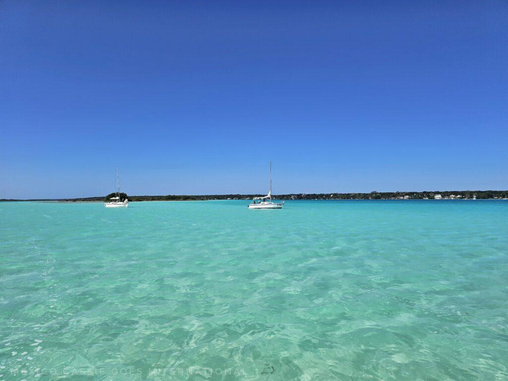 perfect blue water and blue sky, two white boats on horizon and line of land