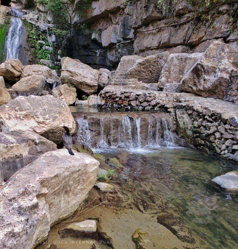 waterfall in very back, rocks and smaller waterfall in front of photo