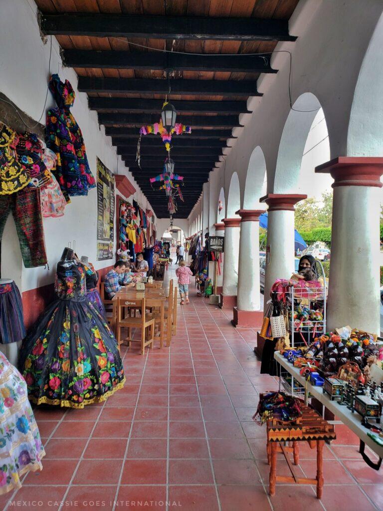 stalls under white arches. red tiled floor, traditional dresses for sale