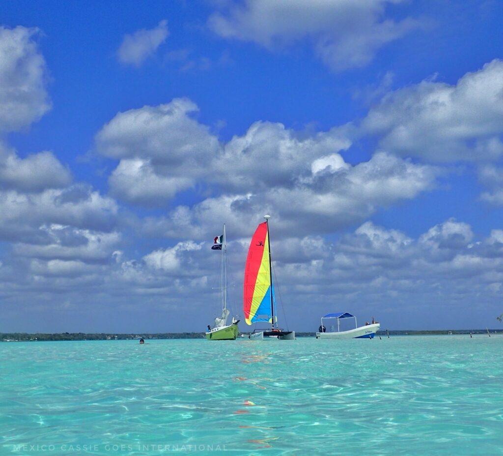 very turquoise water, blue sky, 3 different boats together - catamaran, lancha, sail boat