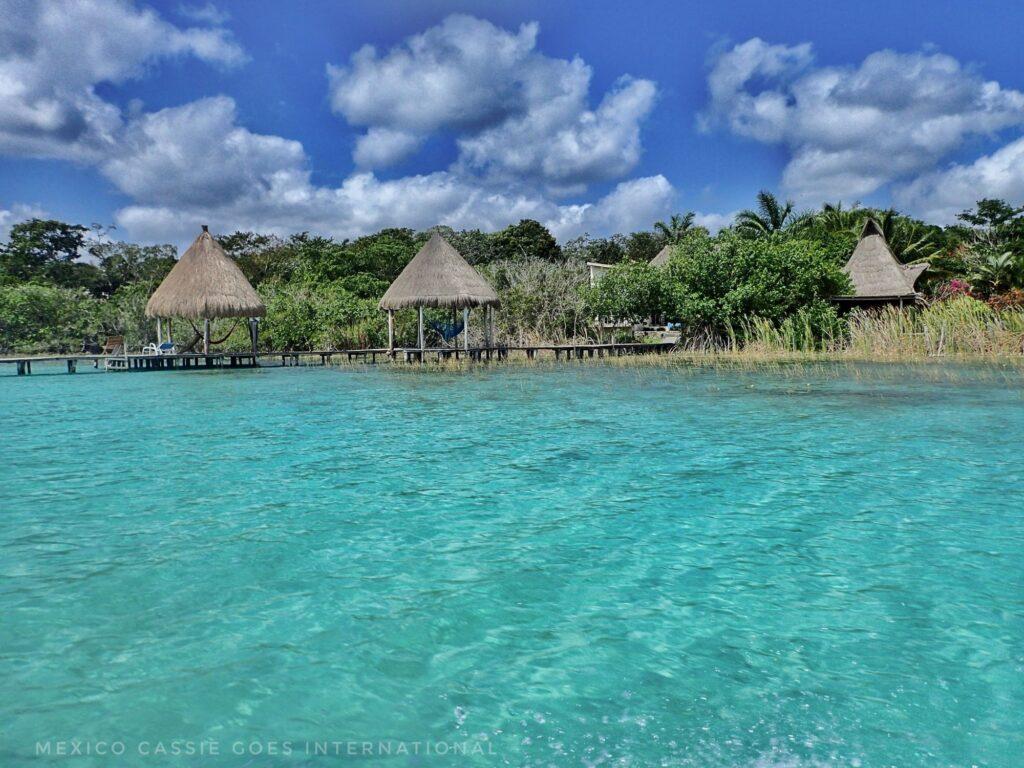 3 thatched huts on piers by turquoise lake