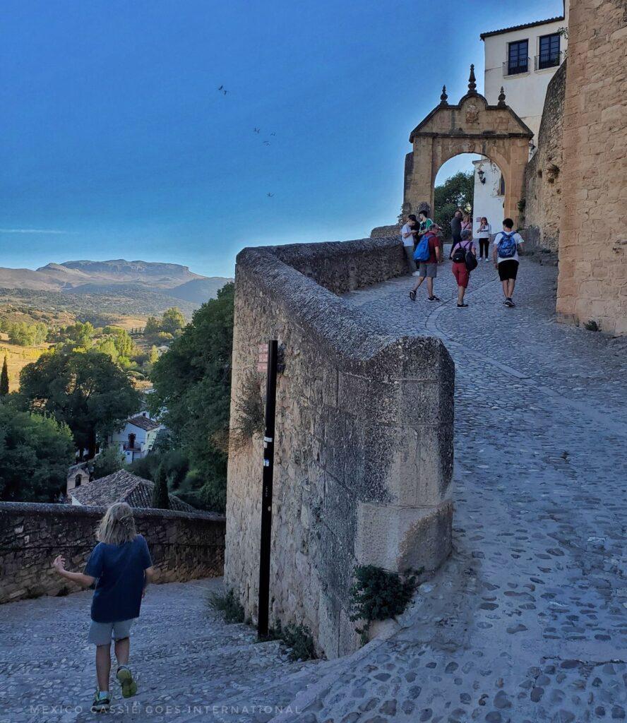 kid walking down sloping path, archway at top of path