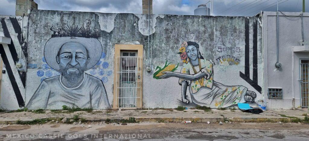 wall art of a woman sitting down holding out a corn husk to an old man