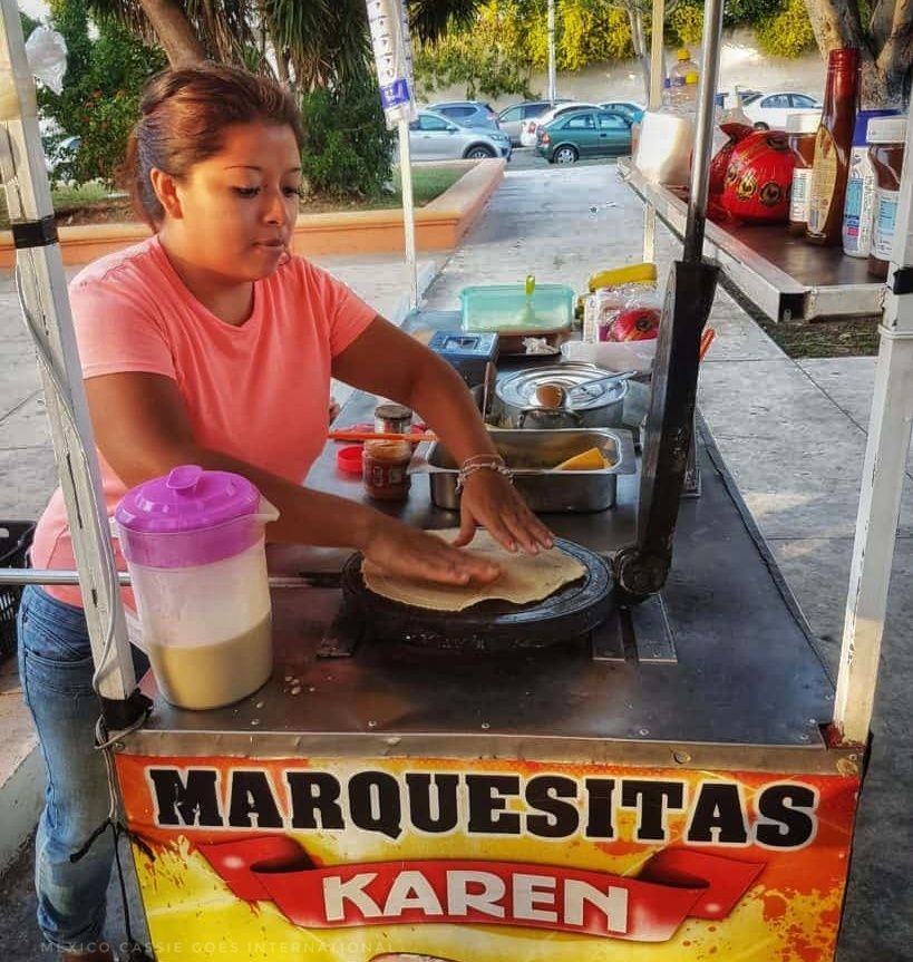 woman making a marquesita at her stall - she has 2 hands on the griddle.