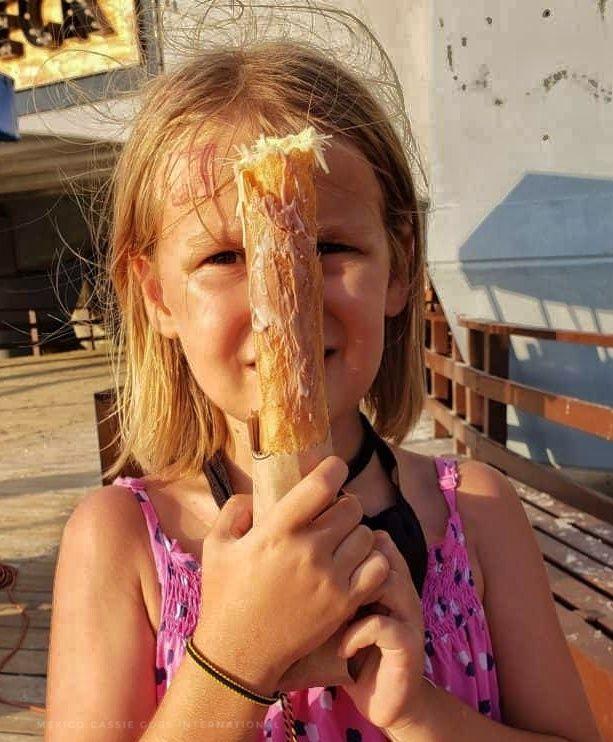 small girl with blonde hair holding a marquesita in front of her face