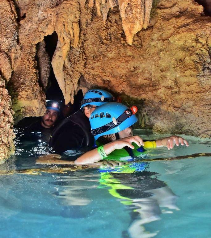 adult and child going backwards through tunnel in cave (in water)