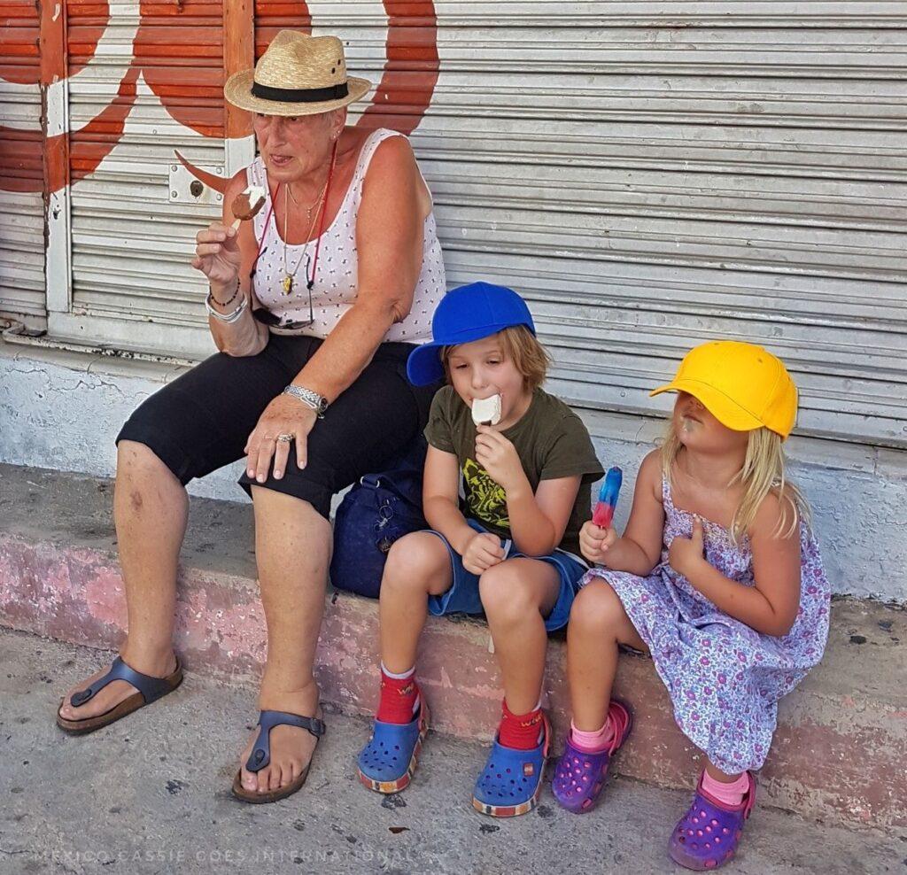 adult woman and 2 kids all in hats sitting eating ice cream