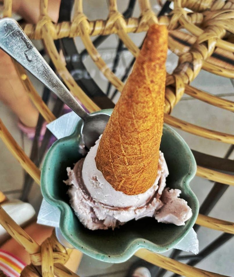 upside down ice cream cone and ice cream scoop in a green bowl with spoon