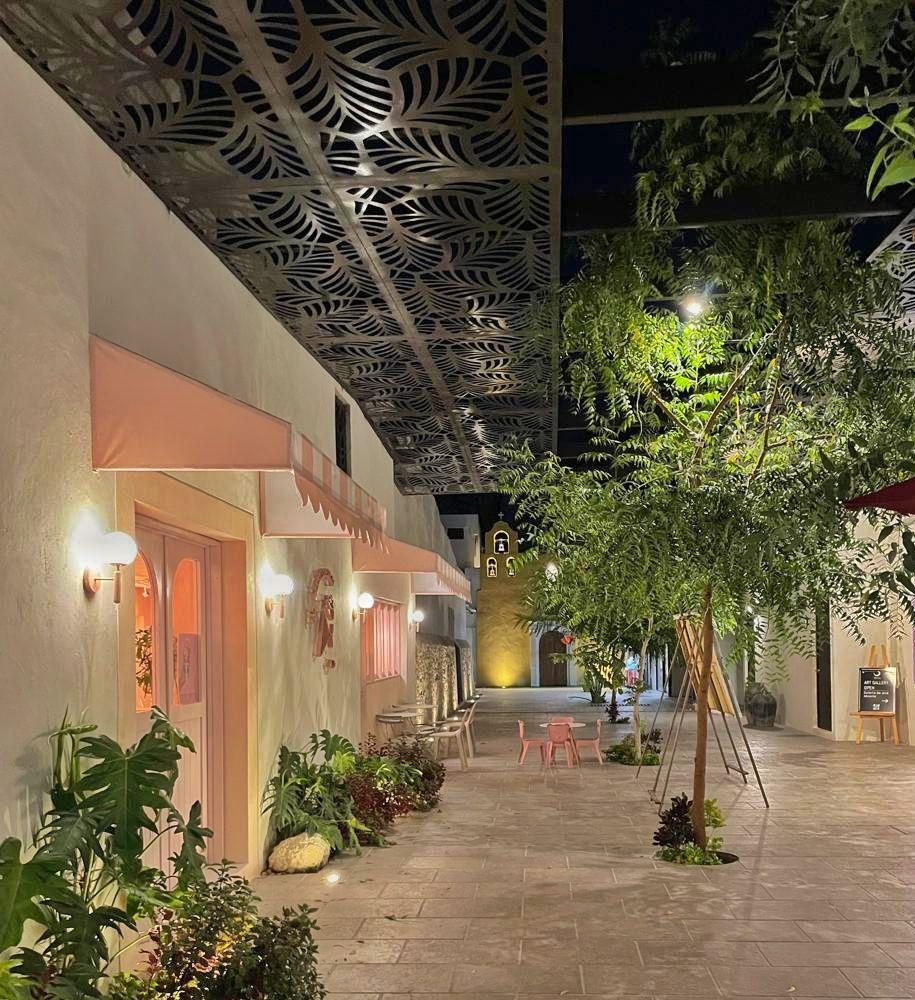 cute courtyard at night - lit trees and pink awnings over pink doors